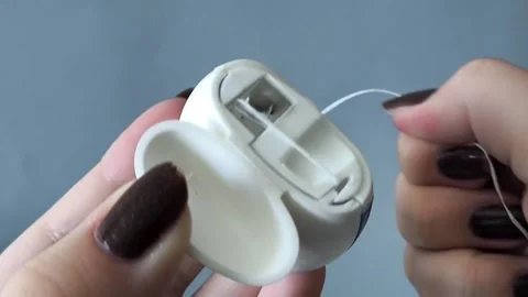 A womans hands pull out and tear the floss out of the container. Flossing to 库存影片 329969566