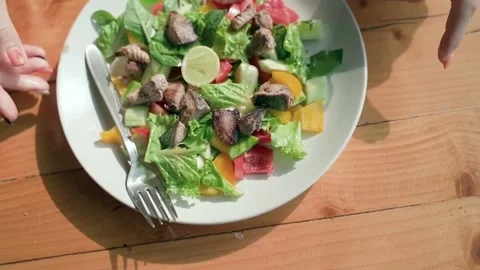 A woman's hands push a white plate of fresh salad aside. Slow motion video. Video stock 234020797