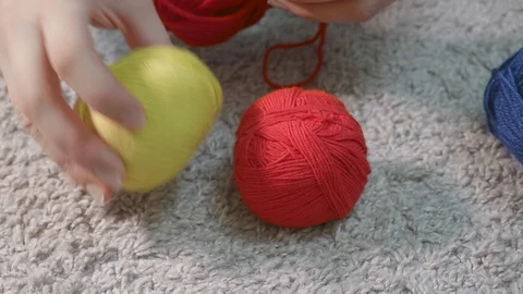Woman's hands put balls of thread for knitting of different colours on the floor Stock Footage 129050726
