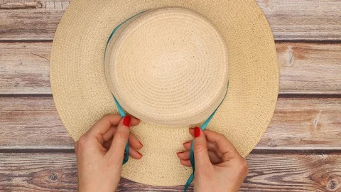 Woman's hands put blue ribbon on hat and tie a bow - Stop motion Stock Footage