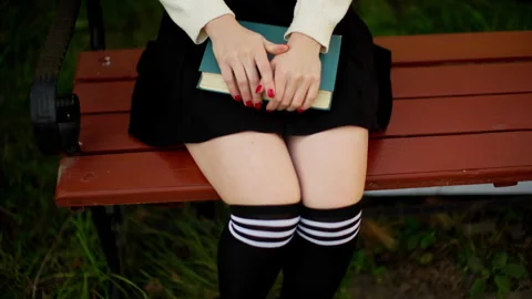 A woman's hands put a book on her lap. Black skirt for students. Stock Footage 253252293