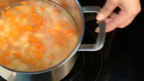 Woman's hands put on the electric stove a pot of soup, include a plate Video stock 78570331