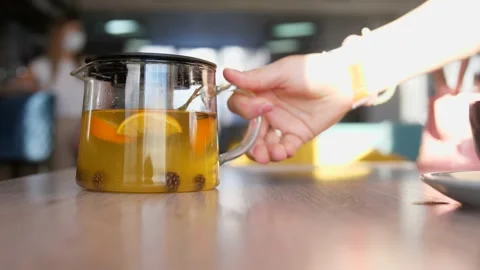 Woman's hands put a pot with hot tea and cup of tea on a wooden table. 4k Stock Footage 150954908