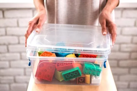 Woman's hands putting colored blocks into box. Stock Photos
