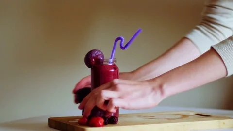 Woman's hands putting three fruit smoothies on the wooden board Video stock 70965158