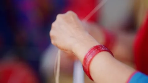 Womans hands with red bangles pulling thread for bead necklace Stock Footage 342399176