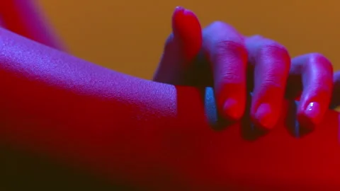 Woman's hands in red-blue led gently touch another hand Stock-Footage 340007736