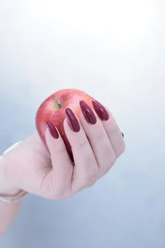 Woman's hands with red long nails are holding a ripe red apple Foto stock