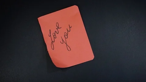 Woman's hands rip appart red page with the words "Love you" written on it. Stock Footage