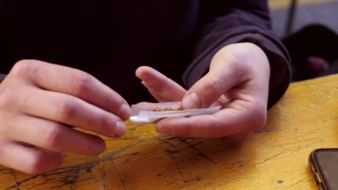 Woman's hands rolling a cigarette with loose tobacco Video stock 320257603