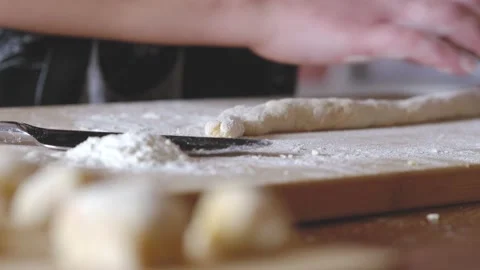Woman's hands rolling the dough for making gnocchi and cutting it Video stock 130768254