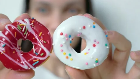 In the woman's hands, round donuts in red and white. Top of the donuts are Stock Footage 148705866