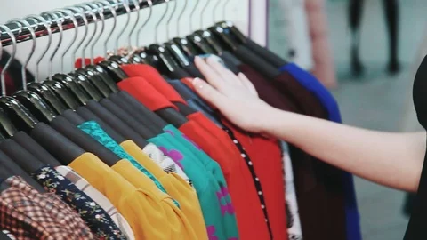 Woman's hands run across a rack of clothes, browsing in a boutique 스톡 동영상 73465875