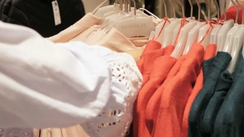 Woman's hands run on across a rack of clothes in store Stock Footage 98423266