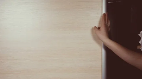 Woman's hands run across a rack of clothes, browsing in the bedroom Stock Footage 101646884