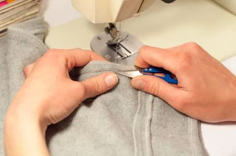 Woman's hands with scissors cut the thread after sewing on the sewing machine Stock Photos