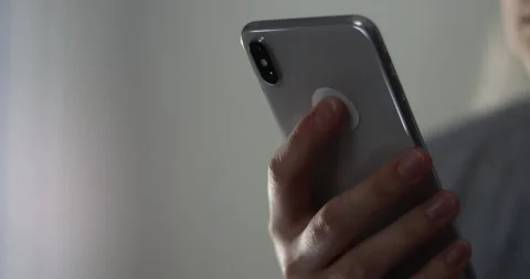 Woman's hands scroll mobile phone keypad to check messages at home in evening Stock Footage 300363841