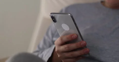 Woman's hands scroll mobile phone keypad to check messages at home in evening Stock Footage 300363864