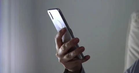 Woman's hands scroll mobile phone keypad to check messages at home in evening Stock Footage 300363868