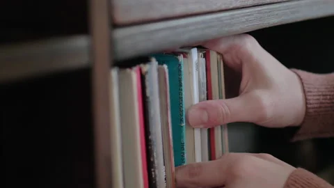 A woman’s hands search through old, retro record albums on a wooden shelf. Stock Footage 155929491