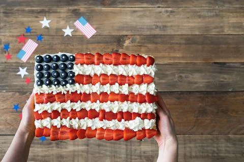 Woman's hands serving square cake with US flag colors on wooden background Foto stock