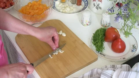 A womans hands skillfully chop fresh young garlic cloves on a wooden cuttin.. Stock-Footage 338408039