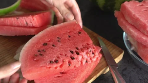 A woman's hands slice and peel a watermelon. Side view, close-up. Stock Footage 344369366