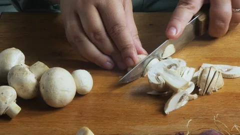 A woman's hands slice champignons on a cutting board on a table. Close-up. 库存影片 330889859