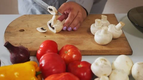 A woman's hands slice champignons on a cutting board. Medium shot. Vidéo 331664244