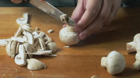 A woman's hands slice champignons on a cutting board on a table. Close-up. 库存影片 347300470