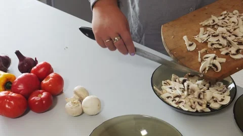 A woman's hands slice champignons with a knife on a cutting board on a tabl.. Stock Footage 331664241