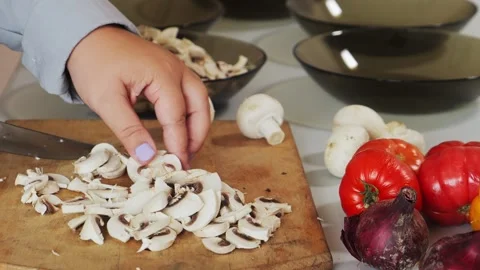A woman's hands slice champignons with a knife on a cutting board on a tabl.. Stock Footage 340472693