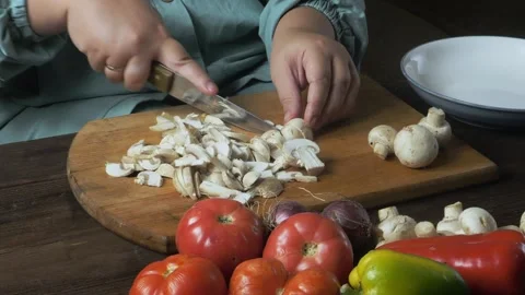 A woman's hands slice champignons with a knife on a cutting board on a tabl.. 库存影片 347016527