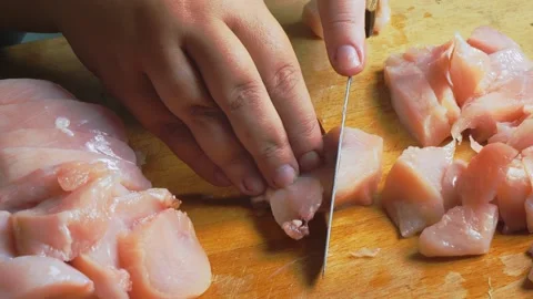A woman's hands slice chicken fillet on a cutting board. Close-up. Stockbeeldmateriaal 347016237