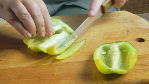 A woman's hands slice green peppers on a cutting board on the table and pla.. Stock Footage 322020306