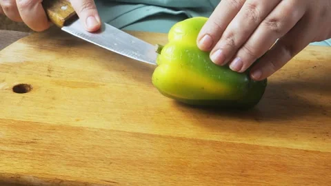 A womans hands slice green peppers on a cutting board on the table Stock Footage 326508946