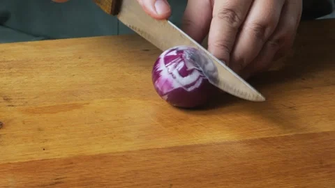 A woman's hands slice a red onion with a knife on a cutting board on the ta.. Stock Footage 322020326