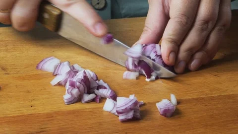 A womans hands slice a red onion with a knife on a cutting board on the table Stock Footage 326509158