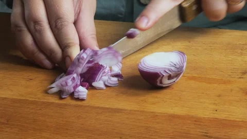 A woman's hands slice a red onion with a knife on a cutting board on the ta.. Stock Footage 338304143