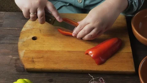 A woman's hands slice red peppers on a cutting board on the table and place.. Stock Footage 322020322