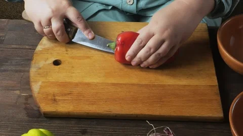 A woman's hands slice red peppers on a cutting board on the table and place.. Stock Footage 329657654