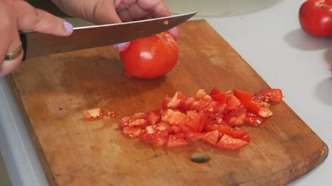 A woman's hands slice red tomatoes on a cutting board on a table. Medium shot Vidéo 322020130