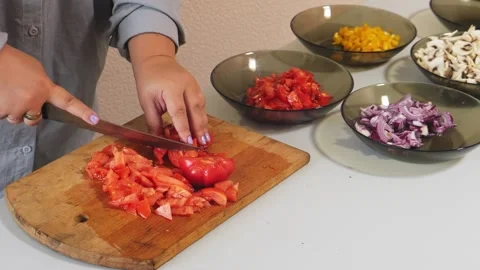 A woman's hands slice red tomatoes on a cutting board on a table with veget.. Stock Footage 322020138