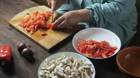 A woman's hands slice red tomatoes with a knife on a cutting board on the t.. 库存影片 322020232