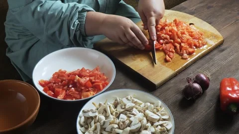 A woman's hands slice red tomatoes with a knife on a cutting board on the t.. Stock Footage 326508158