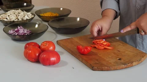 A woman's hands slice red tomatoes on a cutting board on a table. Medium shot 스톡 동영상 342553048