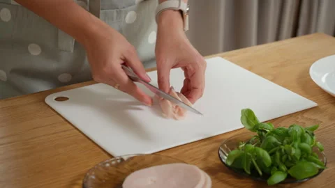 A woman's hands slicing cooked ham with a knife on a white cutting board Vídeos de archivo 315905692