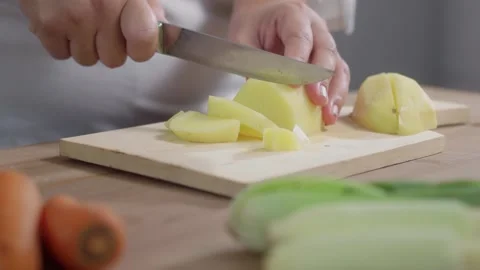 Woman's hands slicing potatoes on a cutting board Stock Footage 329684889