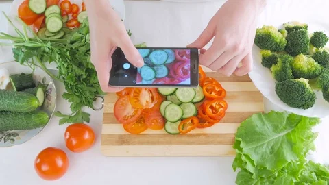 Woman's hands with a smartphone are taking pictures of fresh vegetables for Stock Footage 99813630