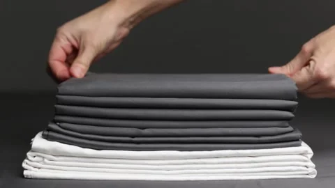 The woman's hands smooth out a stack of folded sheets. Stock Footage 143920249